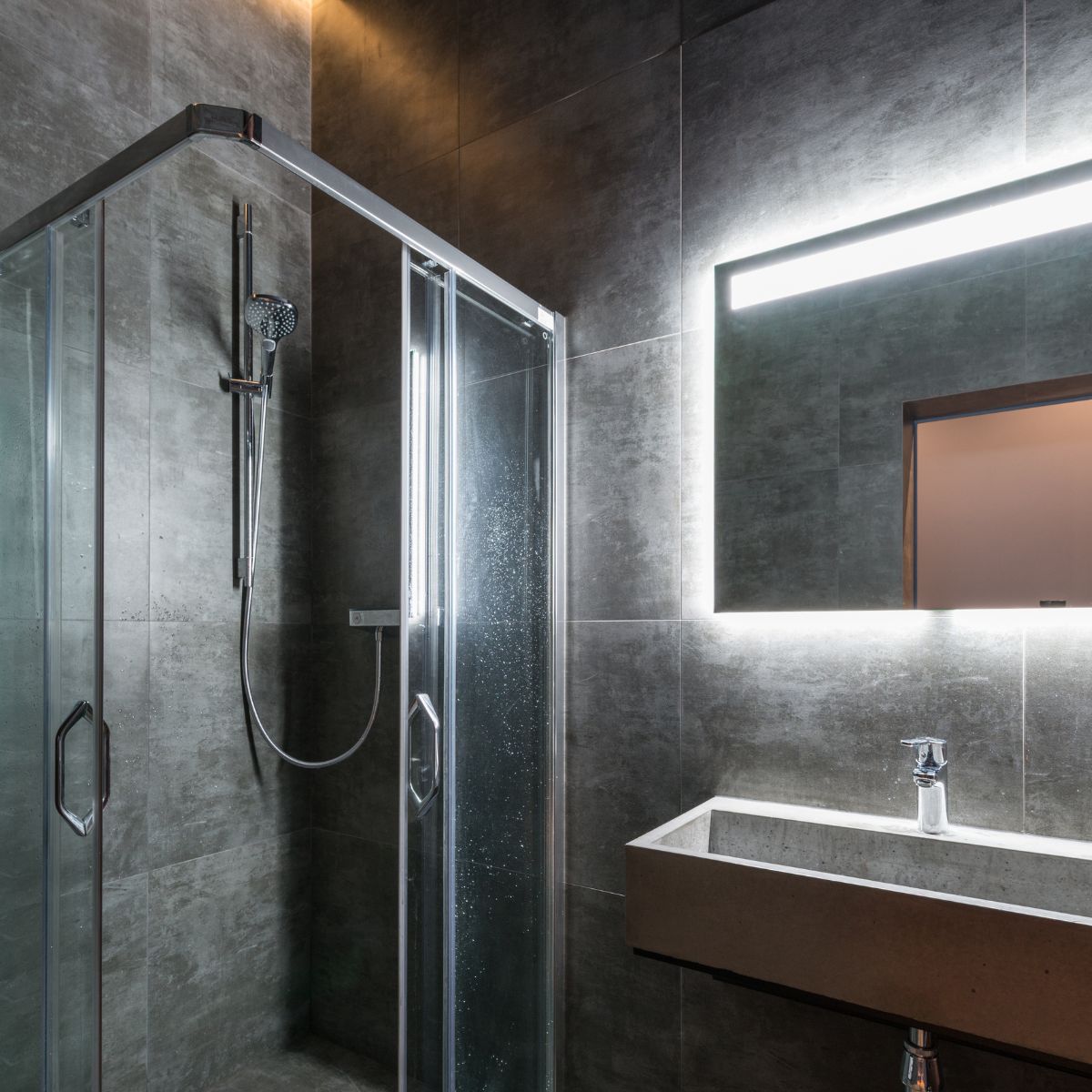 Modern dark-themed bathroom with sleek fixtures, minimalist design, and a contemporary feel, illustrating bathroom renovation mistakes to avoid.