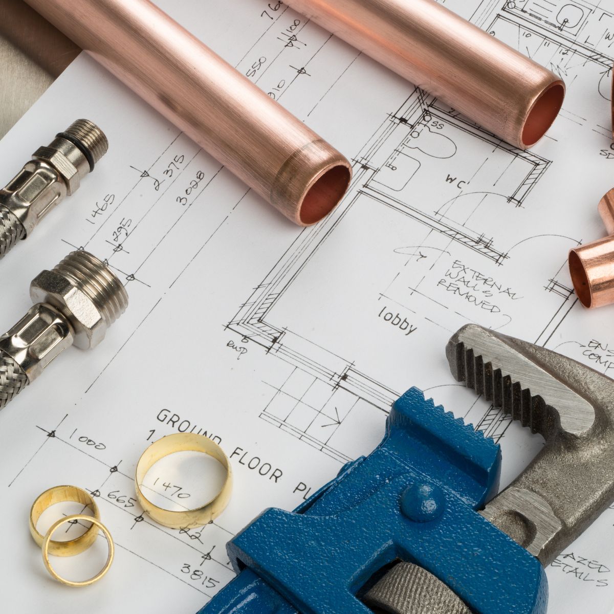 Quality plumbing supplies arranged on a building blueprint, featuring copper pipes, fittings, and a wrench, symbolizing professional and reliable plumbing solutions