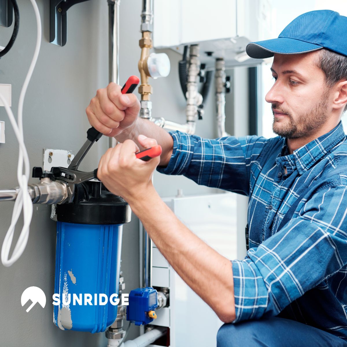 Sunridge plumbing technician installing a blue water filtration system with professional tools — high-quality plumbing equipment and bathroom solutions