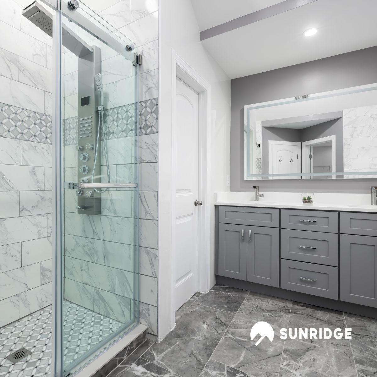 Modern bathroom with glass shower screen and wall mounted shower mixer taps, featuring elegant marble tile design.
