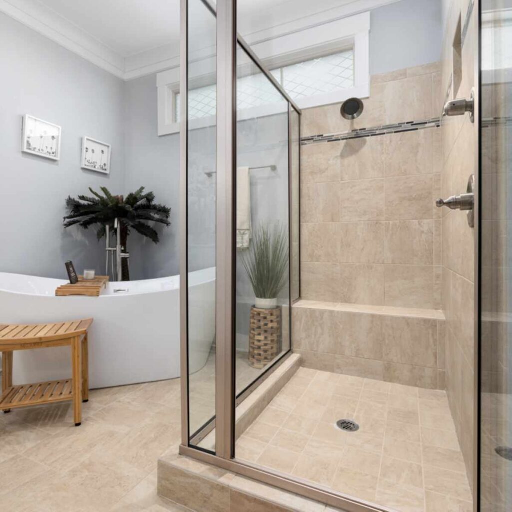 Modern bathroom featuring wall mounted shower mixer taps with a glass shower enclosure and neutral stone tiles for a clean, contemporary look.