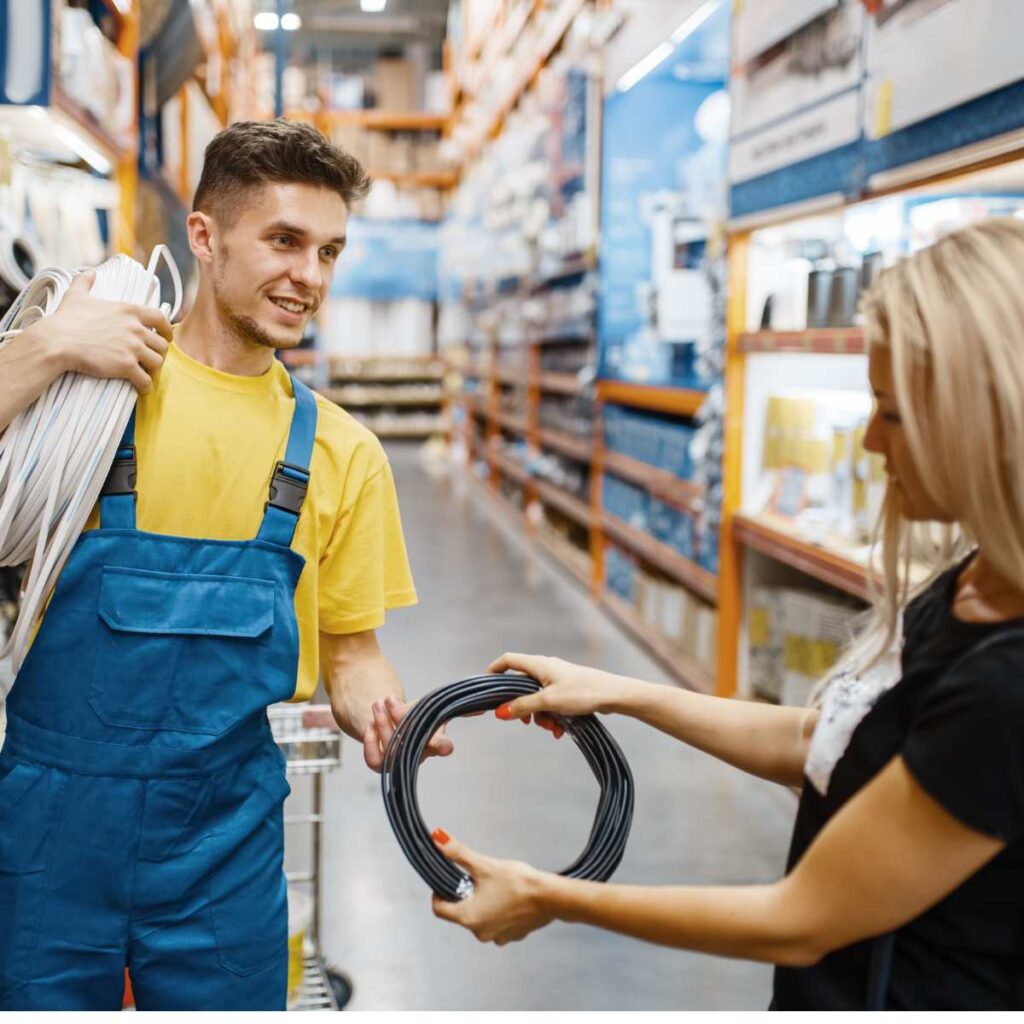 Plumber selecting plumbing supplies with customer in hardware store aisle
