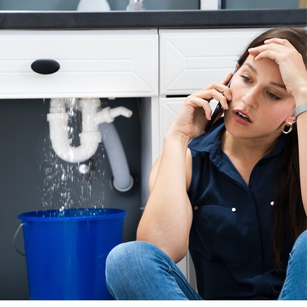 Homeowner dealing with a leaking pipe under a kitchen sink