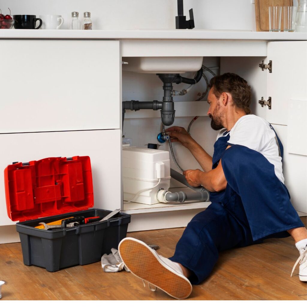 Plumber repairing residential plumbing systems under a kitchen sink